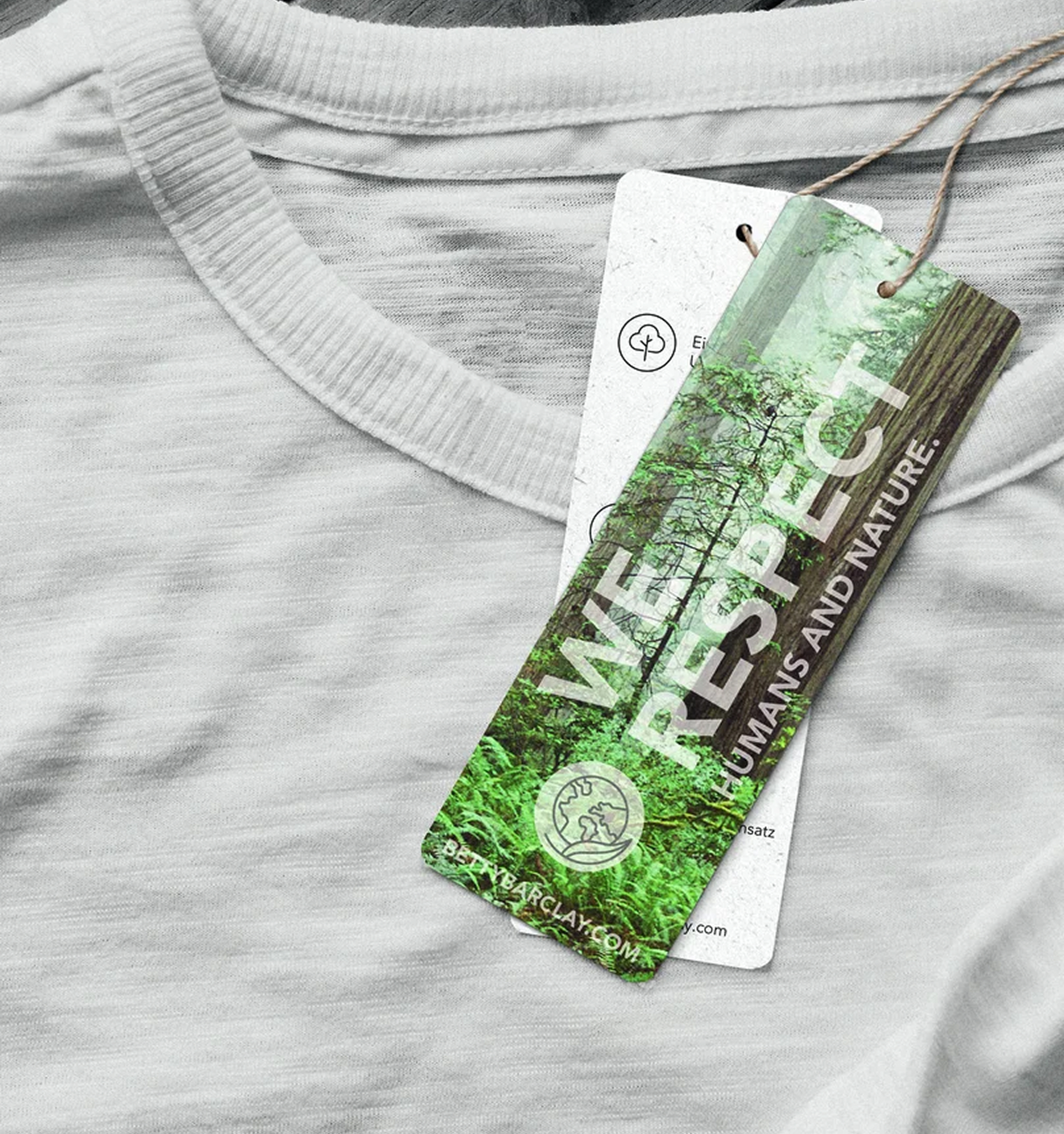 Ein grünes Etikett mit der Aufschrift "We Respect" ist an einem dünnen braunen Faden an einem weißen T-Shirt angebracht. 